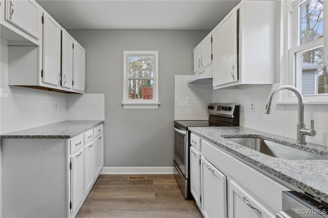 kitchen with sink, light hardwood / wood-style flooring, stainless steel appliances, light stone countertops, and white cabinets