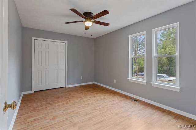 unfurnished bedroom with ceiling fan, light wood-type flooring, and a closet