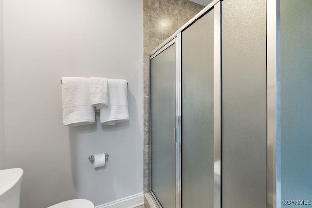 bathroom featuring a shower with door and toilet