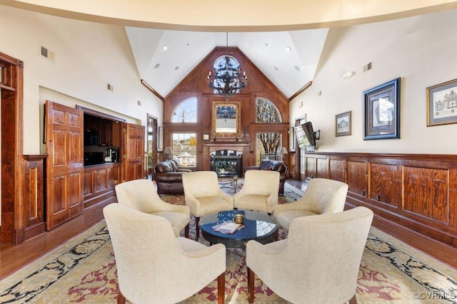 living room featuring light hardwood / wood-style floors, high vaulted ceiling, and a notable chandelier