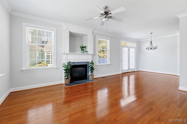 unfurnished living room featuring ceiling fan with notable chandelier, wood-type flooring, ornamental molding, and a premium fireplace