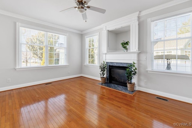 unfurnished living room featuring hardwood / wood-style flooring, a fireplace, ornamental molding, and a healthy amount of sunlight