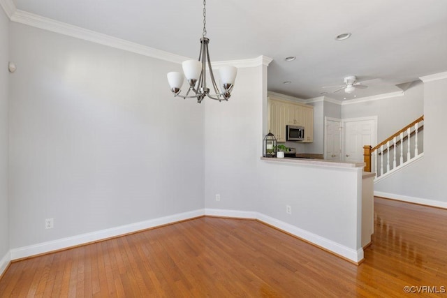 interior space with wood-type flooring, ceiling fan with notable chandelier, and crown molding