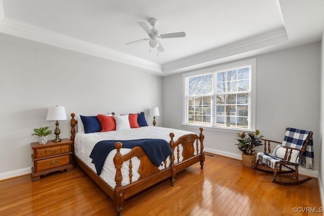 bedroom featuring a raised ceiling, ornamental molding, hardwood / wood-style floors, and ceiling fan