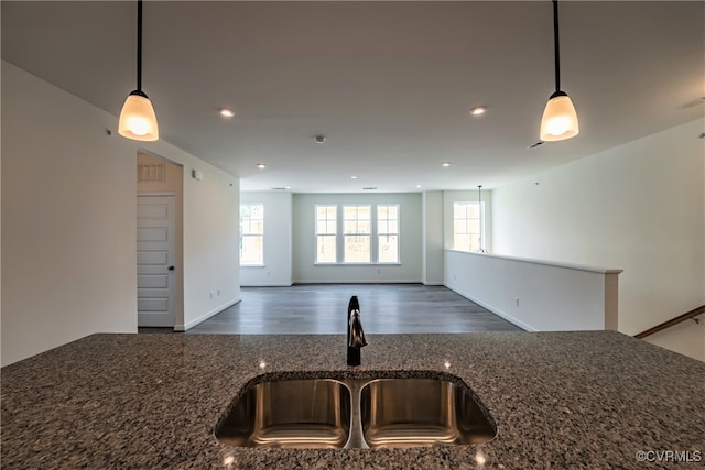 kitchen with pendant lighting, dark wood-type flooring, sink, and dark stone countertops