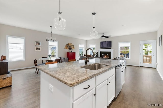 kitchen with pendant lighting, sink, white cabinets, a kitchen island with sink, and stainless steel dishwasher