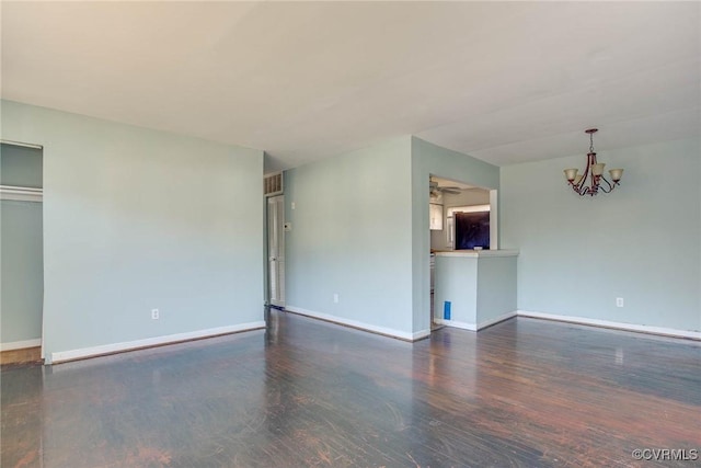 spare room with ceiling fan with notable chandelier and dark wood-type flooring