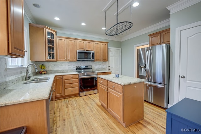 kitchen with sink, crown molding, a center island, appliances with stainless steel finishes, and light stone countertops