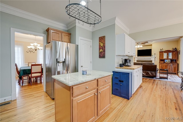 kitchen featuring stainless steel fridge, white cabinets, a kitchen island, decorative light fixtures, and light wood-type flooring