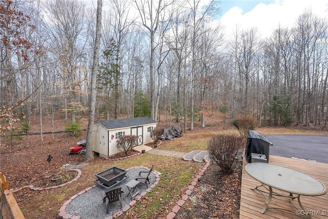 view of yard featuring a storage shed, a deck, and a fire pit