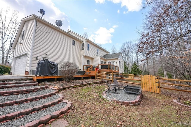 back of property with a garage, a wooden deck, and a fire pit