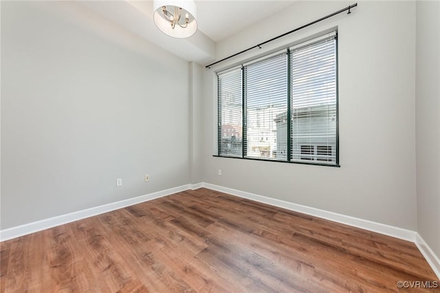 spare room with hardwood / wood-style floors and a chandelier