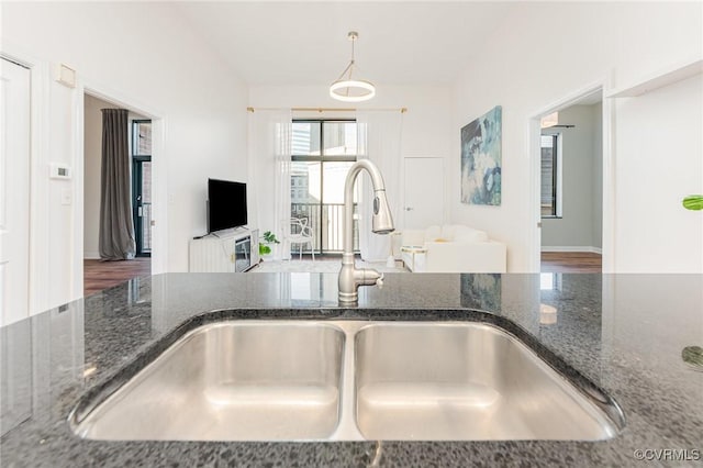 kitchen featuring pendant lighting, dark stone counters, and sink