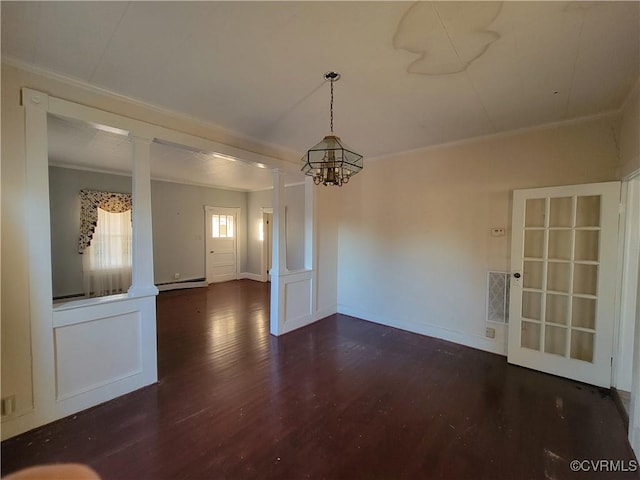 spare room with a chandelier, decorative columns, dark hardwood / wood-style flooring, a baseboard radiator, and ornamental molding