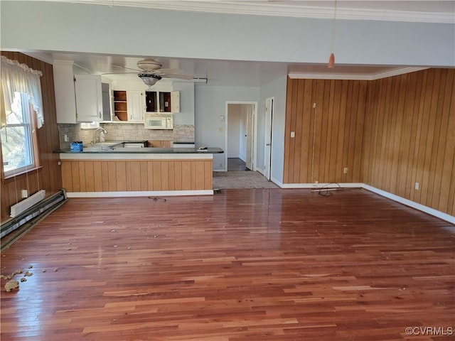 kitchen with tasteful backsplash, white cabinetry, wood-type flooring, sink, and kitchen peninsula