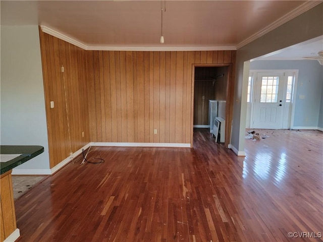 unfurnished dining area featuring crown molding, wooden walls, and dark hardwood / wood-style floors