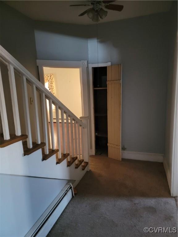 staircase with a baseboard heating unit, carpet floors, and ceiling fan