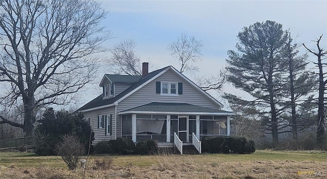 view of front of home with a shingled roof and a sunroom
