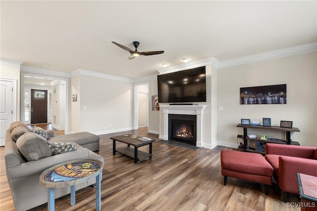 living room featuring wood-type flooring, ceiling fan, and crown molding