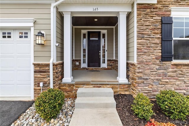 view of exterior entry with a garage and covered porch