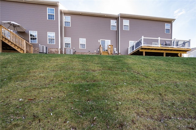 rear view of house featuring a wooden deck and a lawn