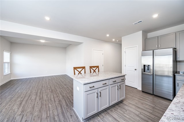 kitchen featuring a kitchen island, stainless steel fridge, light hardwood / wood-style floors, and gray cabinets