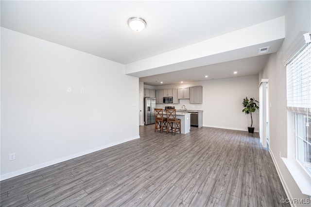 unfurnished living room featuring sink and light hardwood / wood-style floors