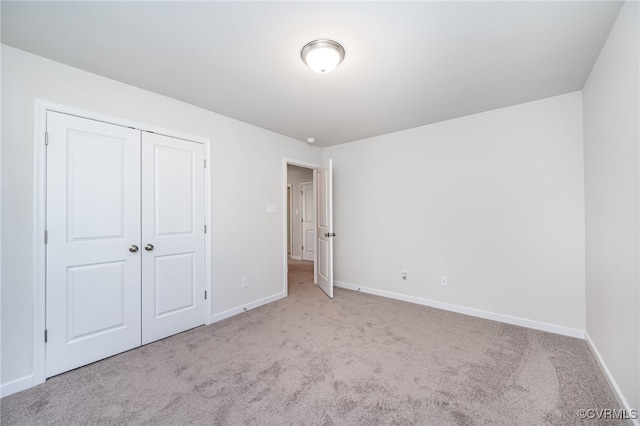 unfurnished bedroom featuring light colored carpet and a closet