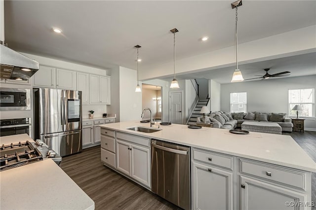 kitchen with sink, a kitchen island with sink, stainless steel appliances, dark hardwood / wood-style floors, and decorative light fixtures