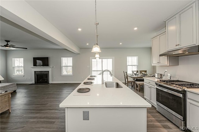 kitchen featuring sink, hanging light fixtures, stainless steel range with gas cooktop, a healthy amount of sunlight, and a kitchen island with sink