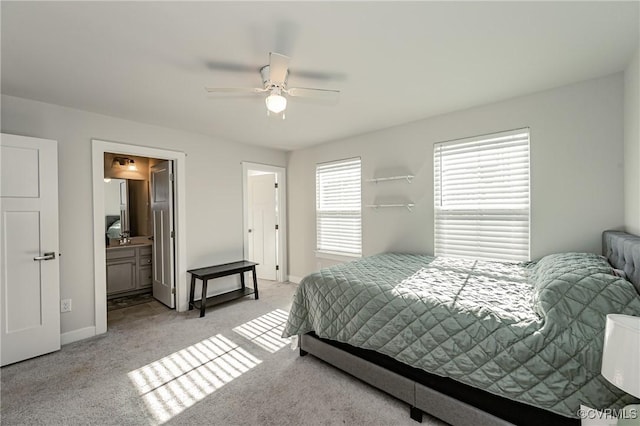 bedroom featuring light colored carpet, ceiling fan, and ensuite bathroom