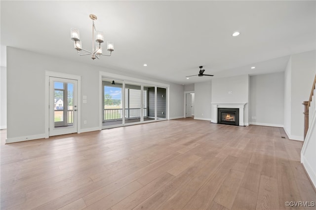 unfurnished living room featuring ceiling fan with notable chandelier and light hardwood / wood-style floors