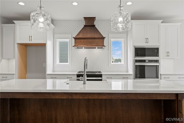 kitchen with decorative light fixtures, custom exhaust hood, white cabinets, and appliances with stainless steel finishes