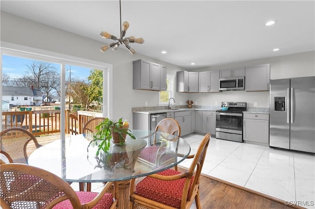 kitchen featuring sink, gray cabinets, stainless steel appliances, and a chandelier