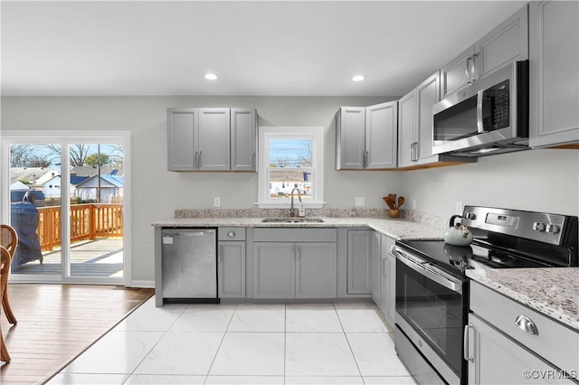 kitchen featuring stainless steel appliances, gray cabinets, sink, and plenty of natural light