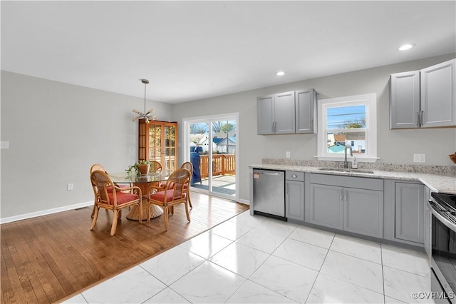 kitchen featuring appliances with stainless steel finishes, gray cabinets, sink, and hanging light fixtures