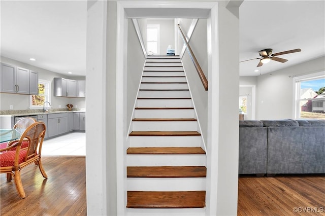 stairway featuring ceiling fan, wood-type flooring, and sink