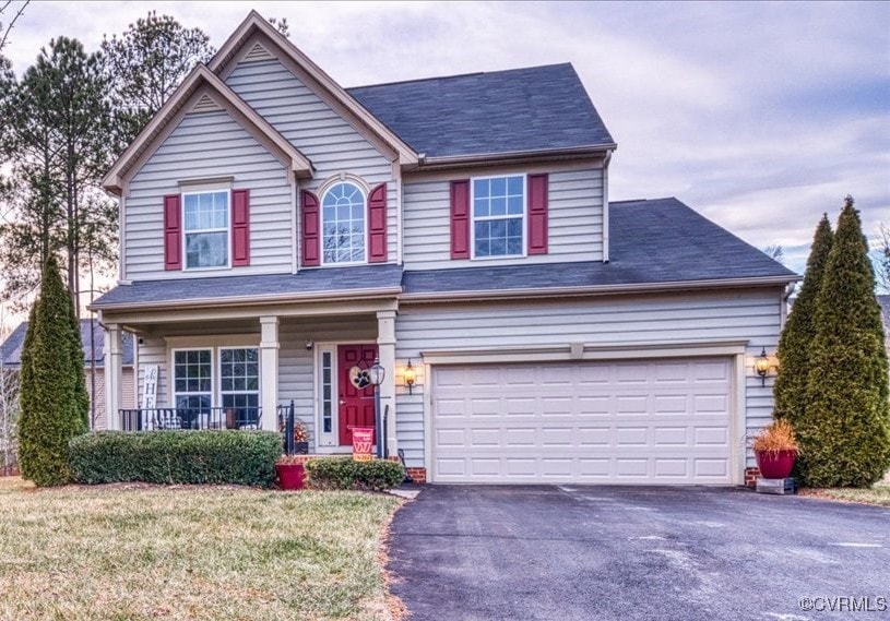 view of front of house with a garage, a front yard, and covered porch