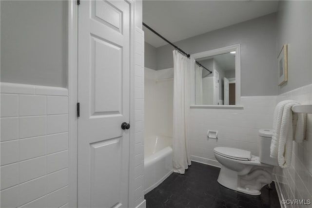 bathroom with tile walls, shower / bath combo, and toilet