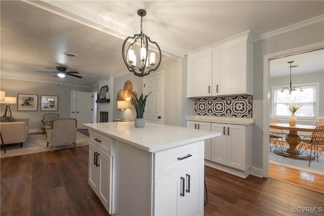 kitchen featuring tasteful backsplash, hanging light fixtures, dark hardwood / wood-style floors, a kitchen island, and white cabinets
