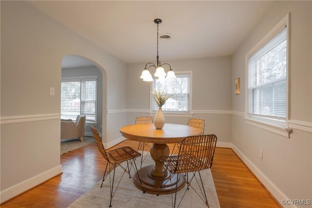 dining area featuring a wealth of natural light, a notable chandelier, and light hardwood / wood-style flooring