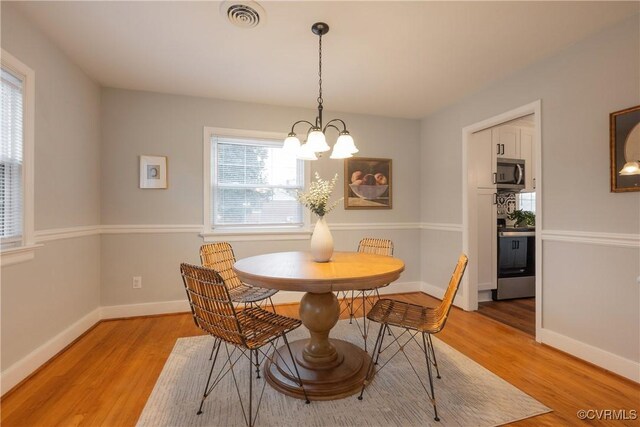 dining space with an inviting chandelier and light hardwood / wood-style floors
