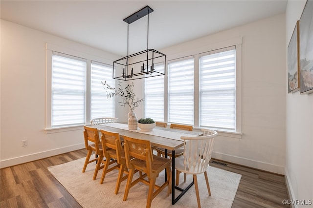 dining space with hardwood / wood-style floors and a chandelier