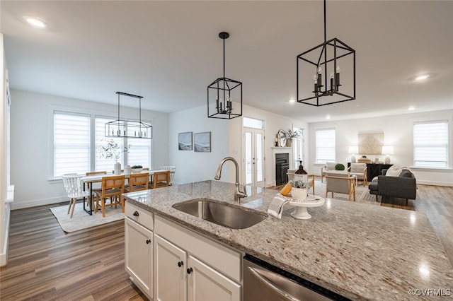 kitchen with white cabinetry, hanging light fixtures, sink, and light stone counters