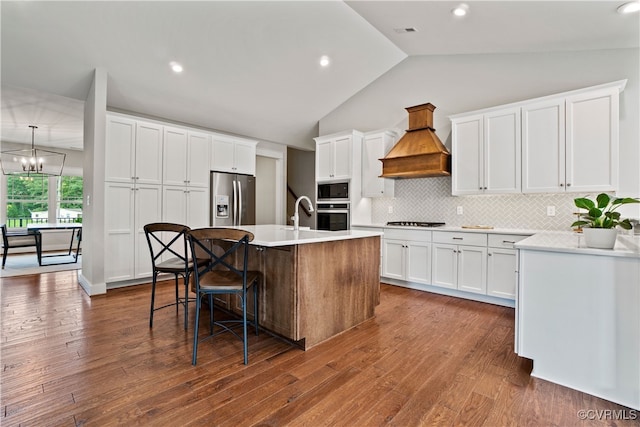 kitchen featuring dark wood-type flooring, a kitchen island with sink, white cabinetry, stainless steel appliances, and custom range hood