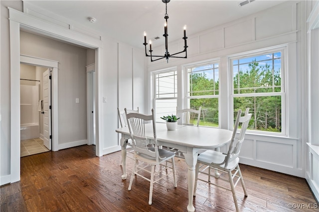 dining space with dark hardwood / wood-style flooring and an inviting chandelier