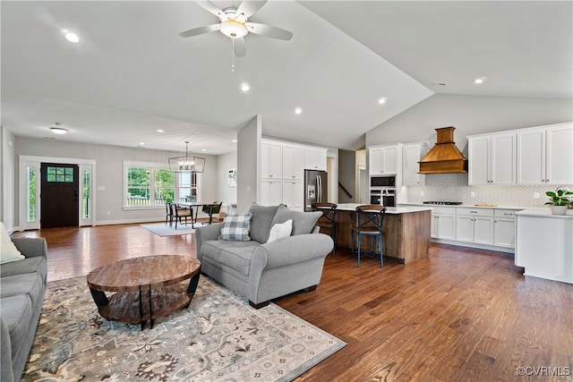 living room featuring lofted ceiling, ceiling fan with notable chandelier, and dark hardwood / wood-style floors