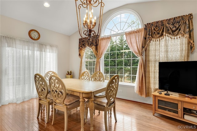 dining space with a chandelier, vaulted ceiling, and light wood-type flooring