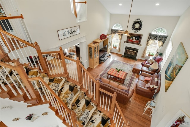 living room featuring hardwood / wood-style flooring, a high ceiling, and ceiling fan