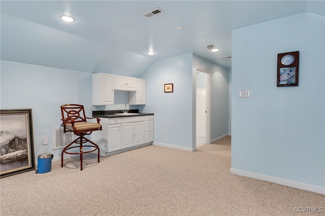 kitchen featuring white cabinetry, sink, light carpet, and lofted ceiling